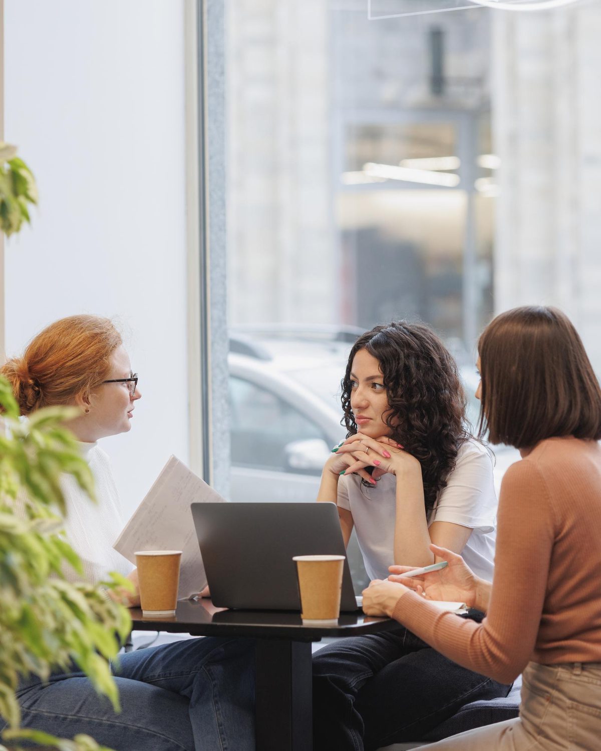 Three women having a strategic IT meeting on managed IT services in a coffee shop