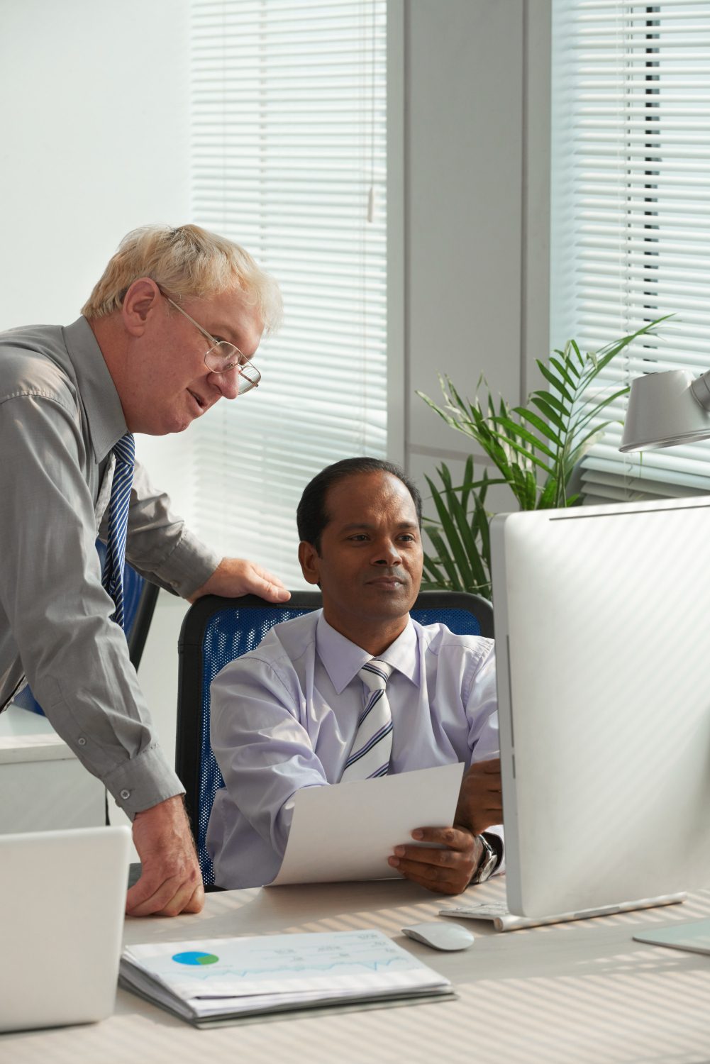 employees sitting in the office at the table and using a laptop